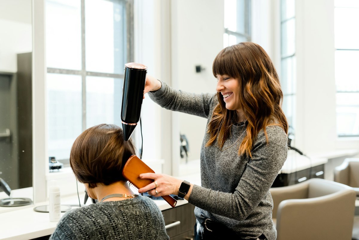 Peluquera secando el pelo a una clienta en su salón