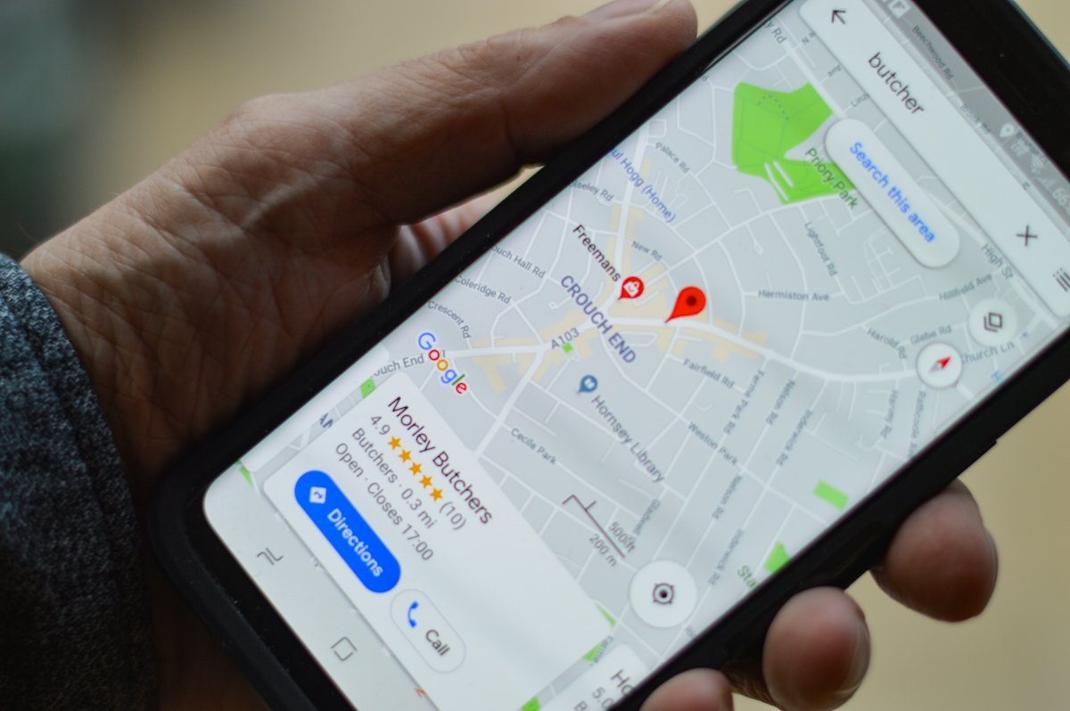 Mano sujetando un móvil con la ficha de un negocio en Google Maps